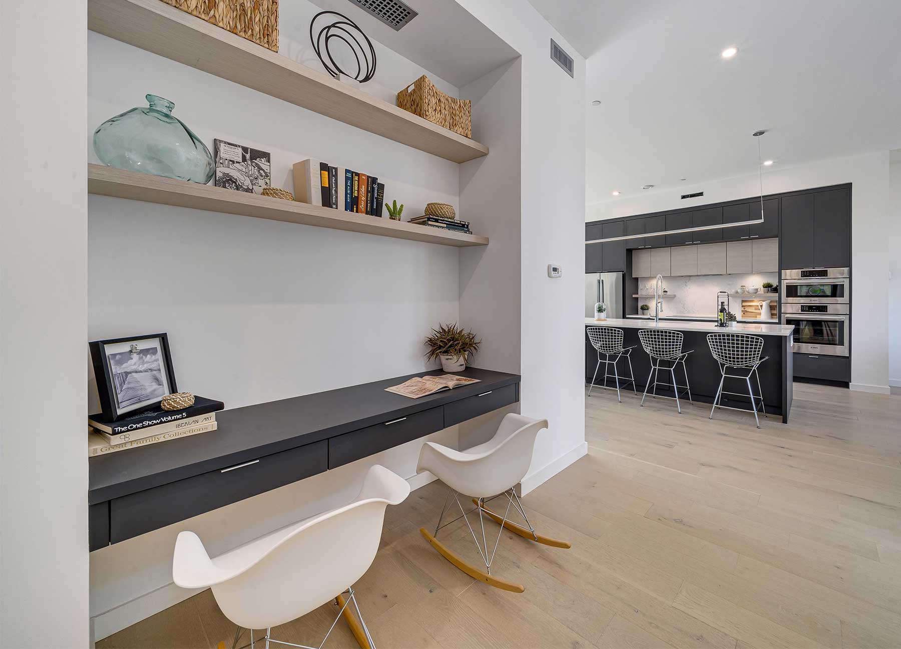 Светлое встроенное рабочее место Baron с открытыми полками и видом в кухню с островом.