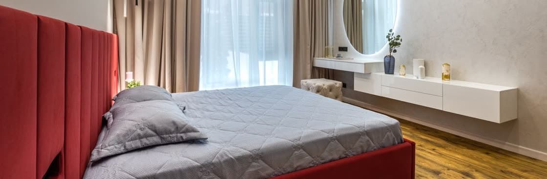 Спальня с красным мягким изголовьем и туалетным столиком